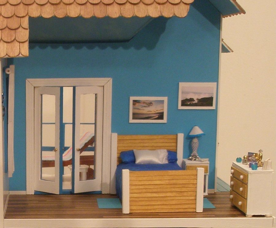 Miniature blue bedroom scene with bed, French doors, nightstand, dresser, and framed wall art