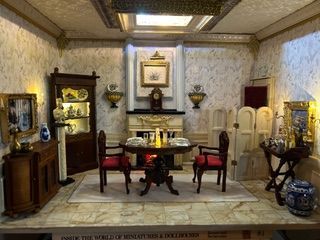 Antique parlor with ornate furniture, marble-topped table, framed art, and decorative cabinets