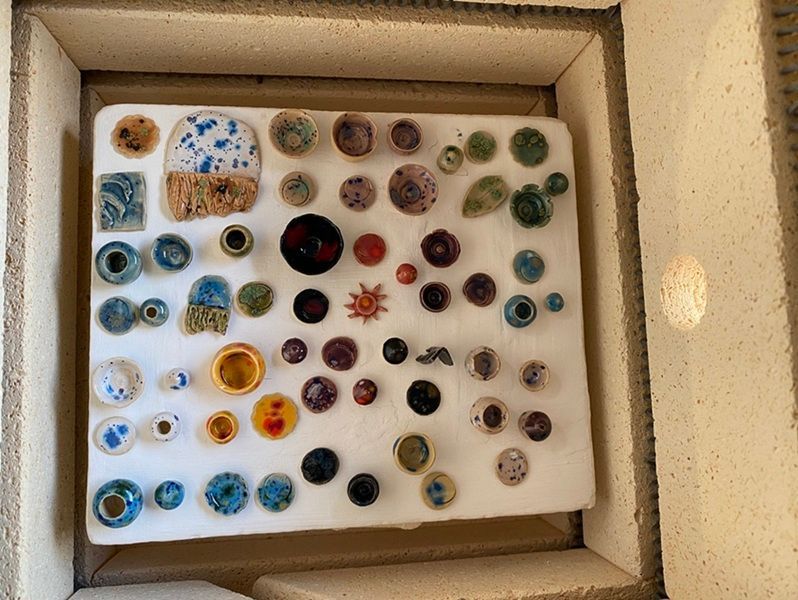 A tray of assorted colorful glass beads or cabochons arranged in rows on white foam.