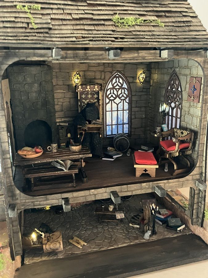 Medieval-style dollhouse interior with rustic kitchen, arched windows, and small furniture on two levels
