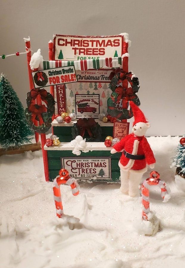 Christmas display with trees, snow, and Santa figurines in front of boxed decorations.