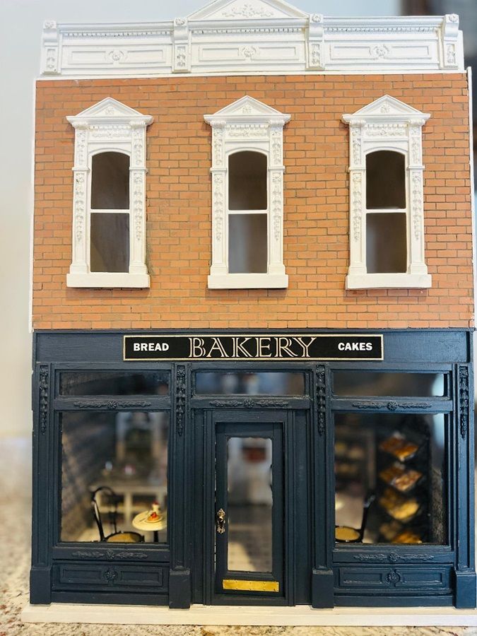 Miniature bakery storefront with orange brick facade, white windows, and black display windows and doors.
