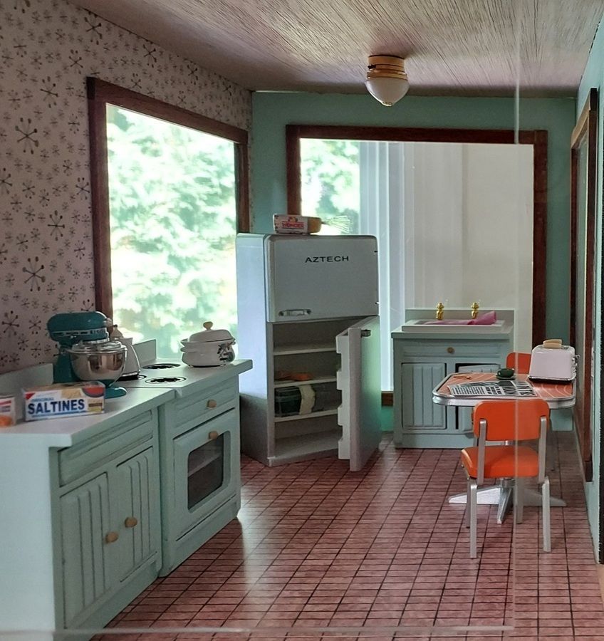 Vintage mint-green kitchen with retro appliances, tiled floor, and a small table by the window