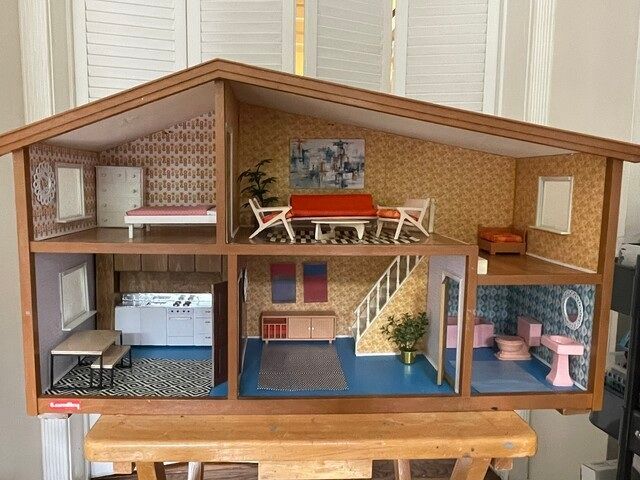 Open dollhouse with five furnished rooms in pastel colors