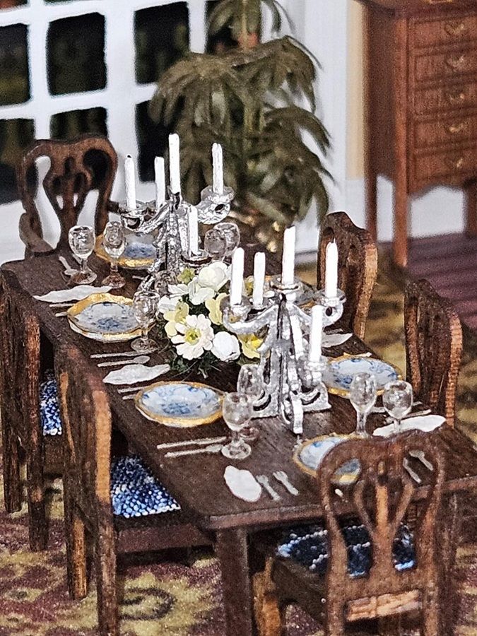 Formal dining table set with silver candelabras, white candles, and floral centerpiece in a dining room