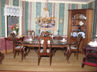 Victorian dining room with ornate wooden table, chandelier, striped wallpaper, and china cabinet