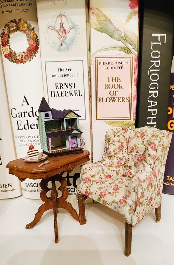 Floral armchair and small wooden table beside stacked books in a cozy, book-themed display