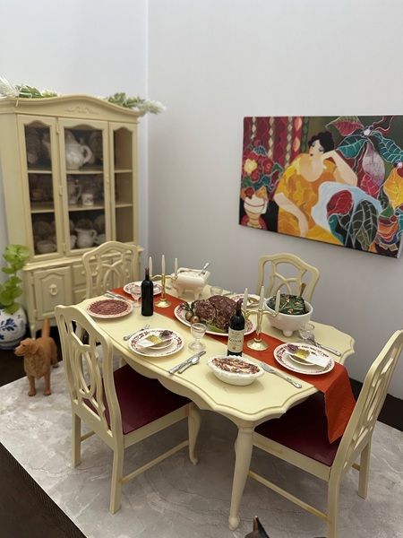 Elegant dining room with set cream table, red cushions, wine bottle, cabinet, and colorful wall art.