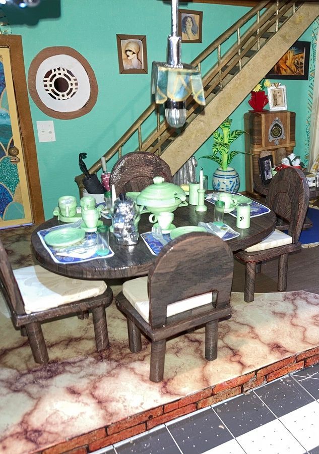 Dining table set with teal dishes and chairs in a turquoise room under a staircase