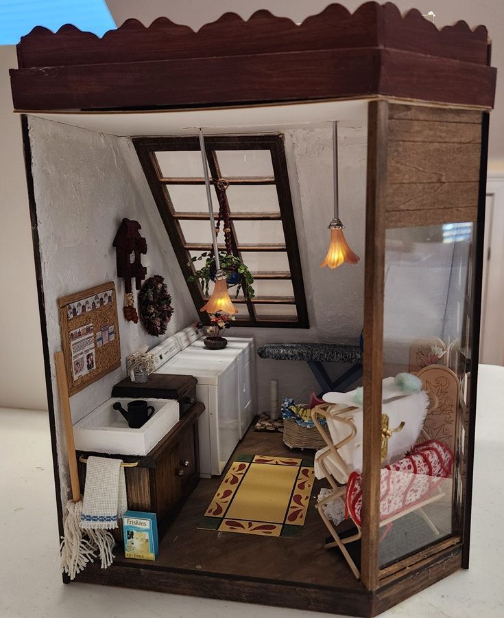 Miniature room diorama with a bed, sink, ladder loft, warm hanging lights, and a windowed corner.