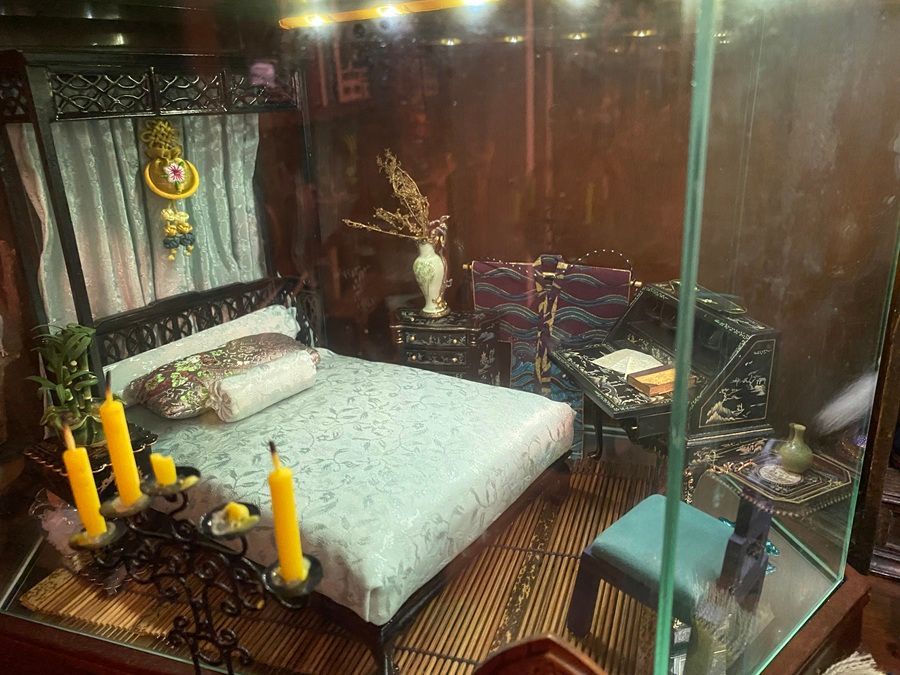 Elegant bedroom with a black bed, light blue bedding, candles, and ornate decor behind a glass partition