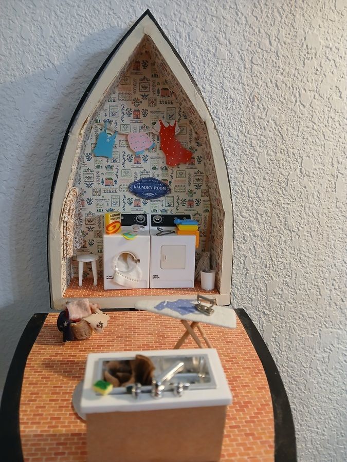 Decorative paper boat diorama with small toy rooms and a miniature figure inside.
