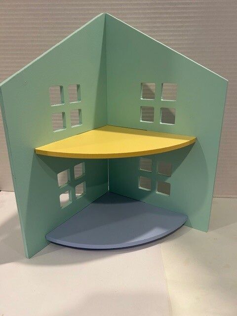 Small pastel paper house model with mint walls, yellow shelf, blue floor, and cutout windows
