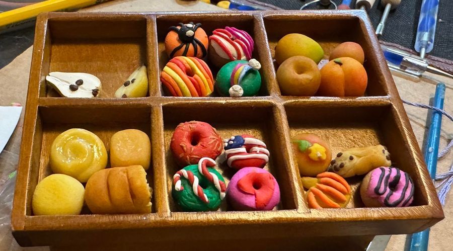 Wooden tray of assorted colorful miniature donuts and pastries in divided compartments