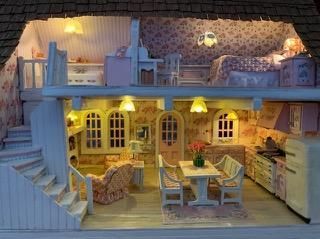 Miniature dollhouse interior with cozy kitchen, dining area, staircase, and warm yellow lighting