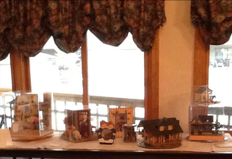 Miniature building display on a windowsill with curtains and bright daylight behind it