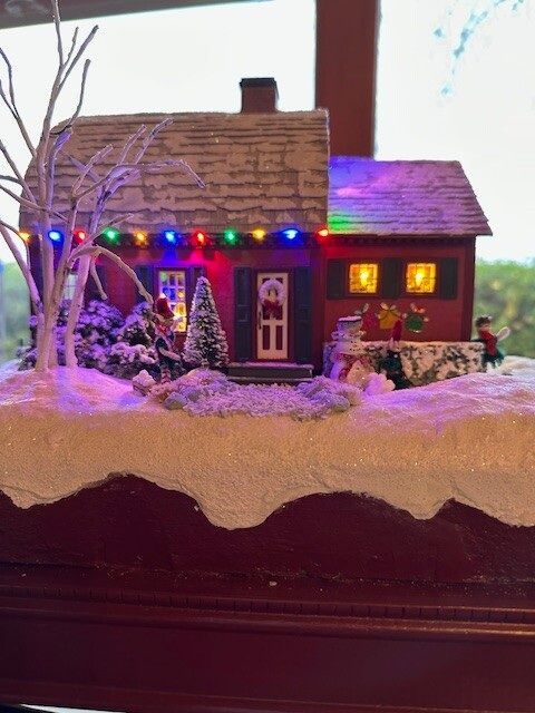 Miniature snow-covered house decorated with colorful Christmas lights on a tabletop display