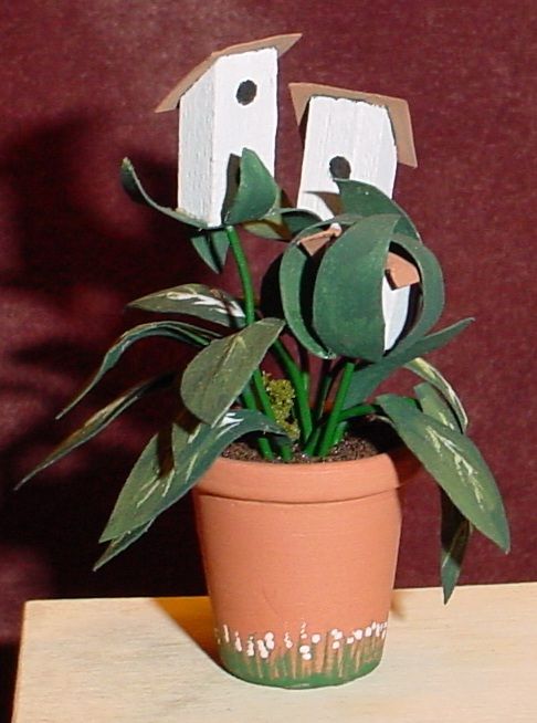 Potted plant with green leaves and two white birdhouse decorations on a table