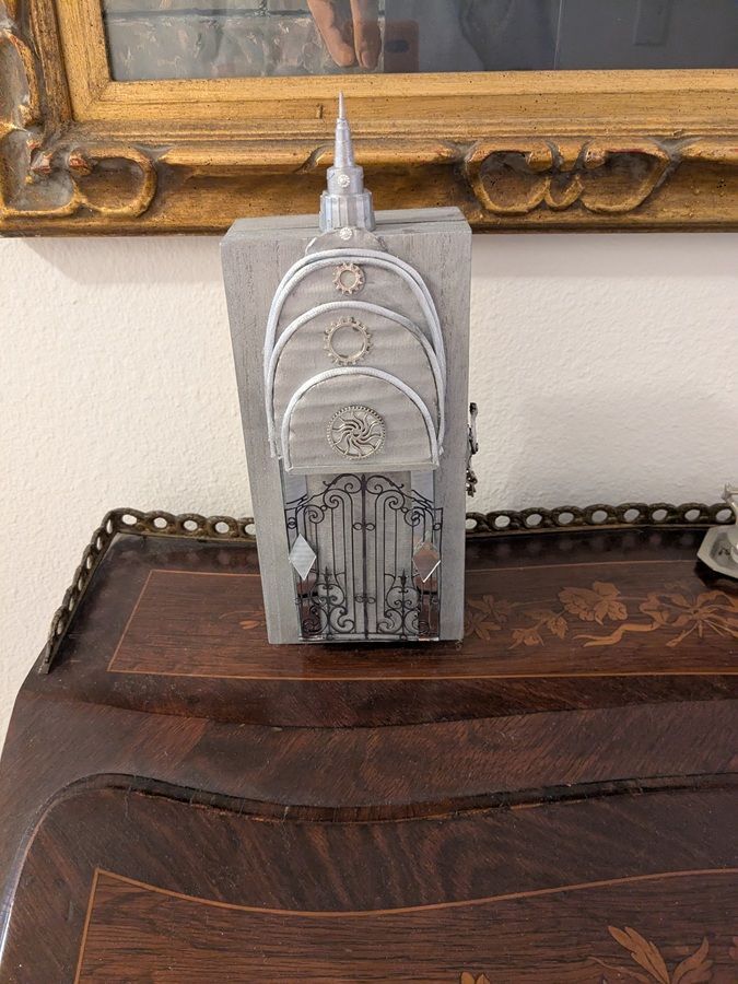 White decorative tower on a dark wooden table in front of a framed mirror