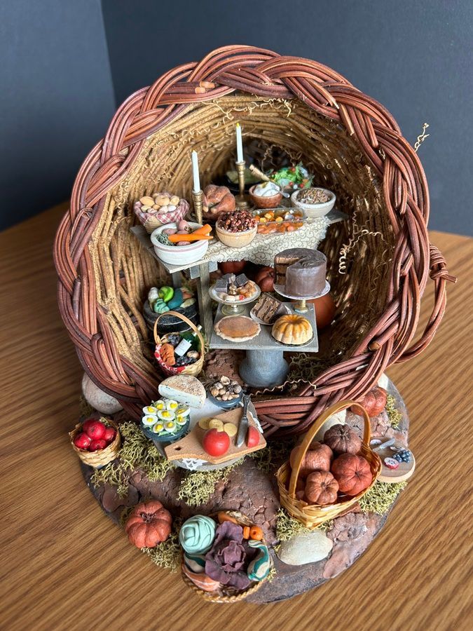 Miniature wicker basket display with tiny food and craft items arranged inside and around it