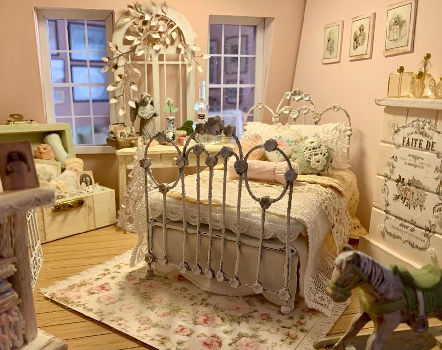 Pastel pink vintage-style bedroom with ornate metal bed, floral decor, and soft furnishings