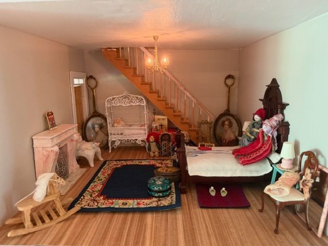 Living room with two ornate beds, staircase, fireplace, and decorative chairs in a beige interior.