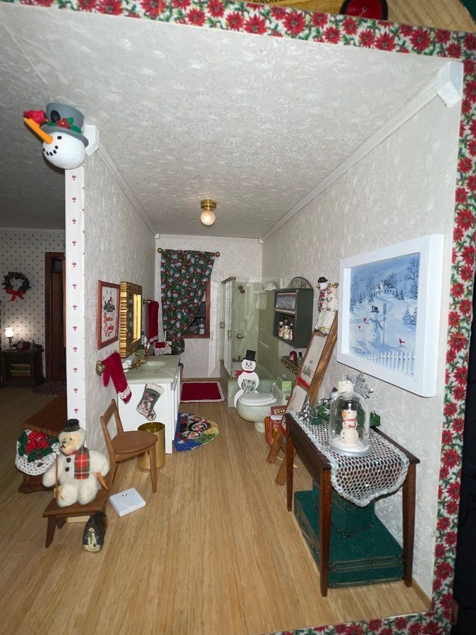 Holiday-themed dollhouse miniature room with wooden floor, patterned walls, and tiny furnishings