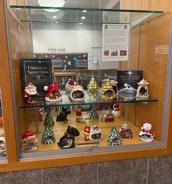 Glass display case with assorted Christmas figurines and ornaments, including Santa and holiday trees.