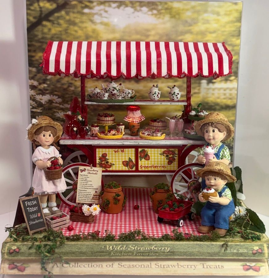 Miniature strawberry market stall with red-and-white awning, doll figures, baskets, and strawberries on display.