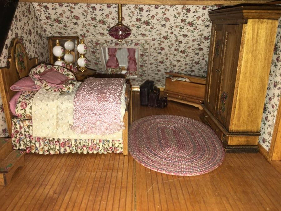 Vintage bedroom with floral wallpaper, wooden bed, armoire, and pink rugs