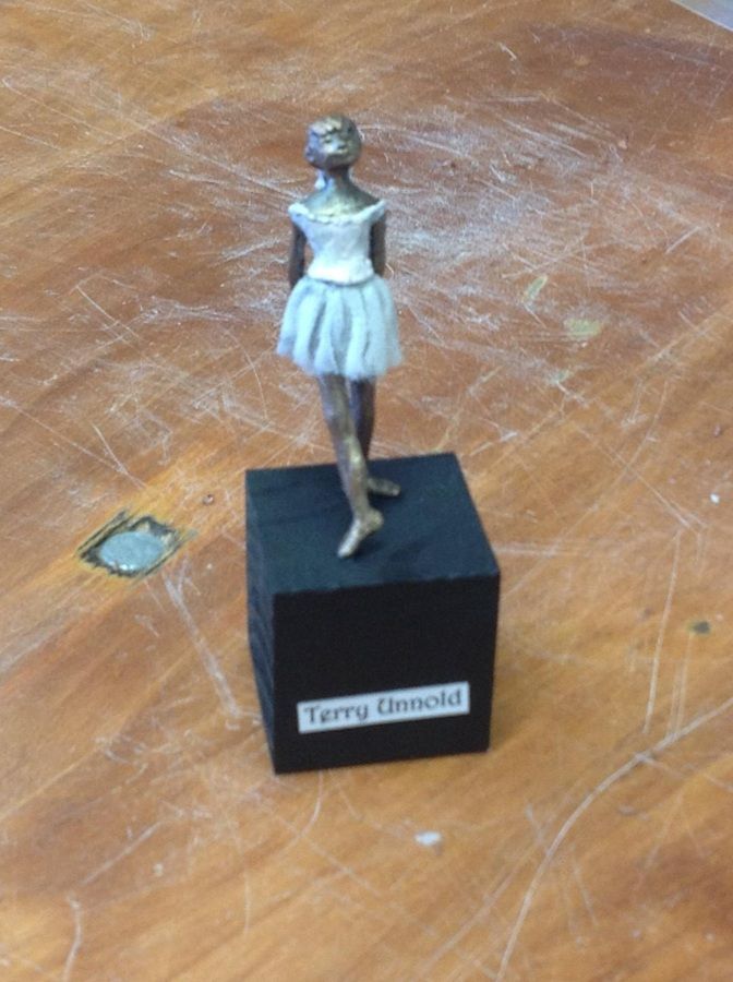 Small figurine of a ballerina on a black base on a wooden table.