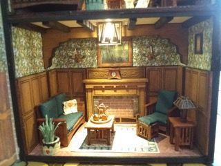 Cozy miniature living room with green couches, wood paneling, fireplace, and central coffee table