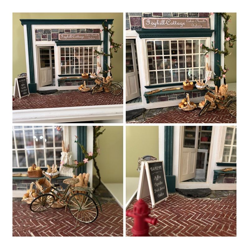 Miniature storefront diorama with white-framed windows, a bicycle, and a sidewalk chalkboard sign