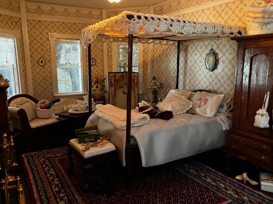 Vintage bedroom with a canopy bed, patterned wallpaper, wooden furniture, and red patterned rug