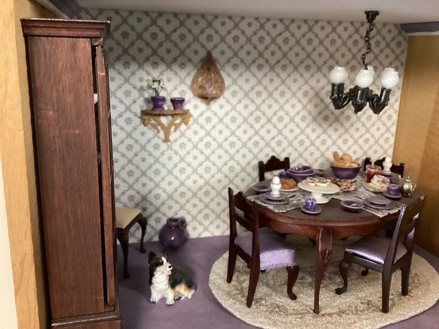 Dining room with a set table, wooden cabinet, chandelier, and a black-and-white cat on the floor