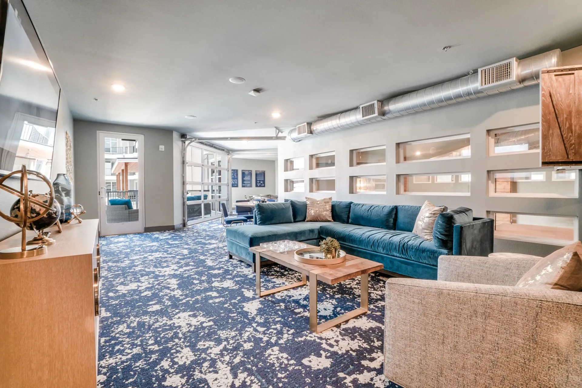 Interior communal lounge with a blue sectional sofa, coffee table, and lounge chairs.