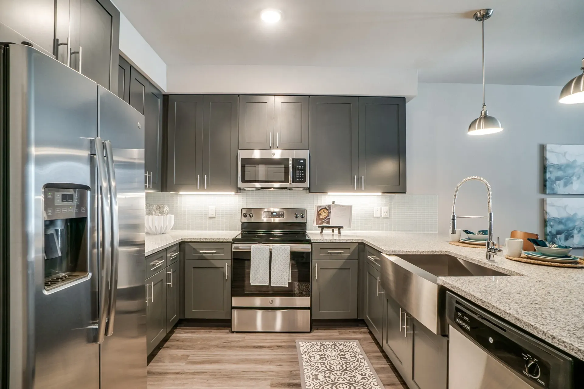 Modern apartment kitchen with stainless steel appliances and gray cabinetry.