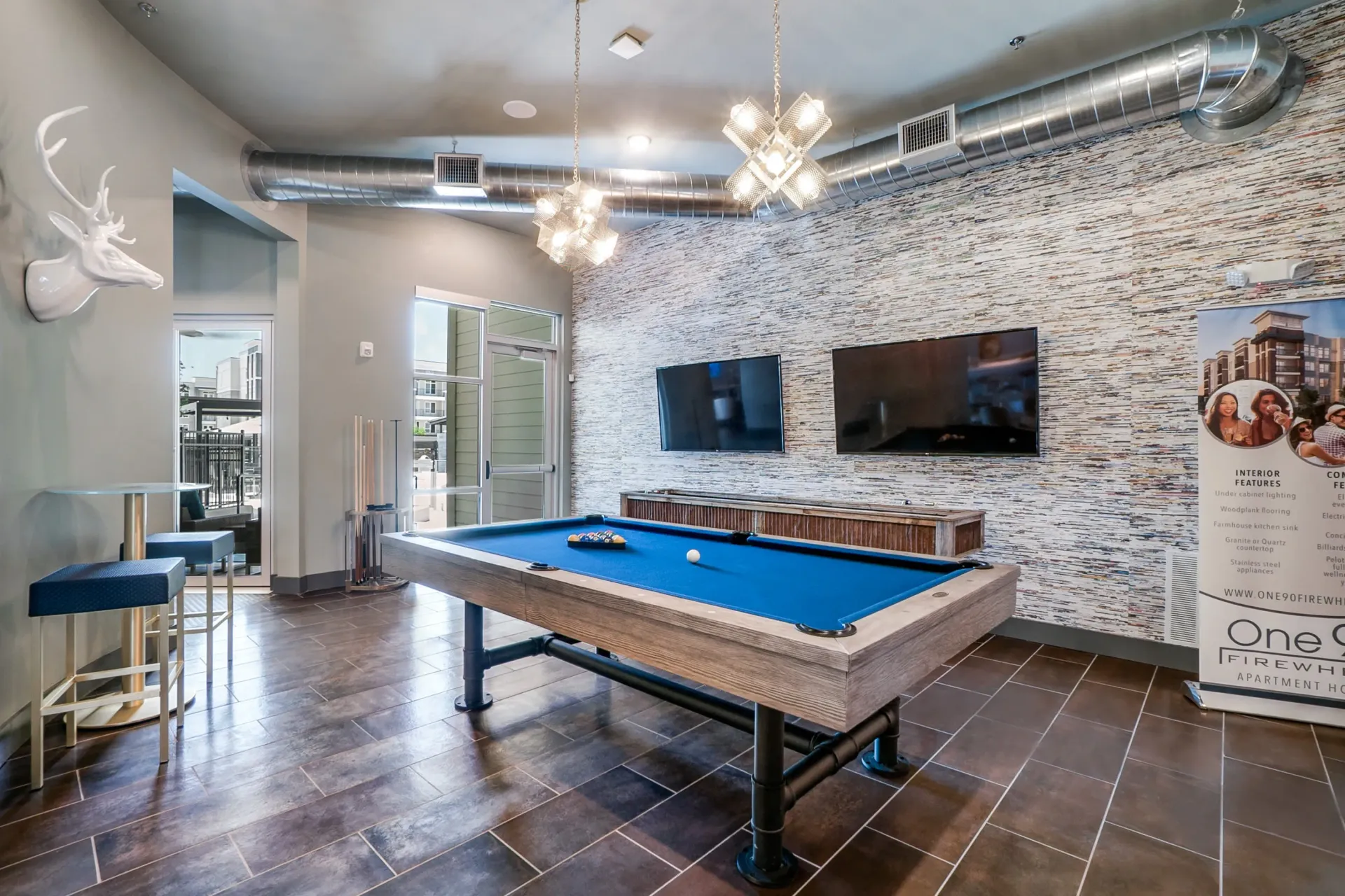 Indoor community recreation room with a pool table, TVs, and modern decor.