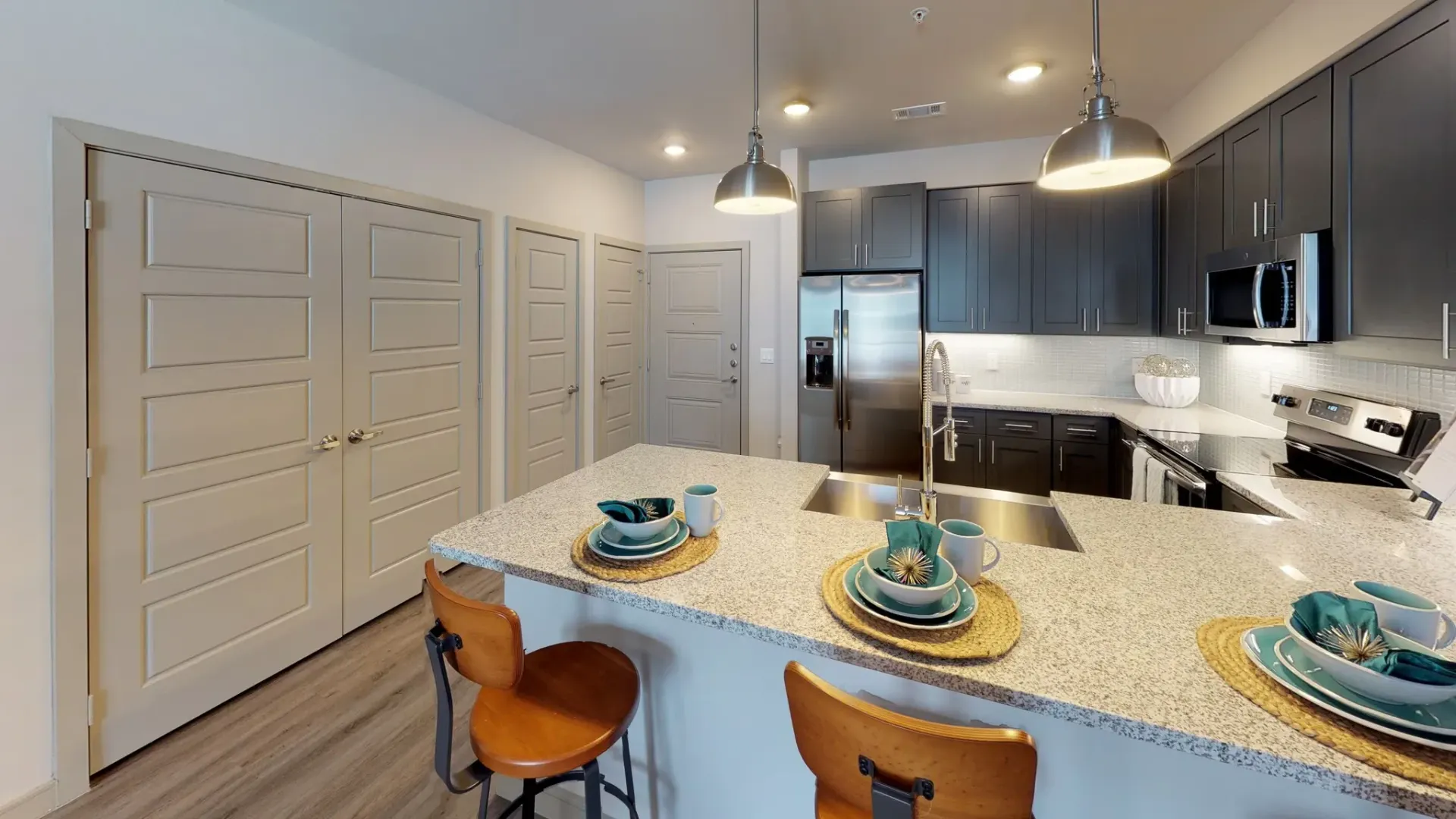 Modern apartment kitchen with island, granite countertops, and stainless-steel appliances.