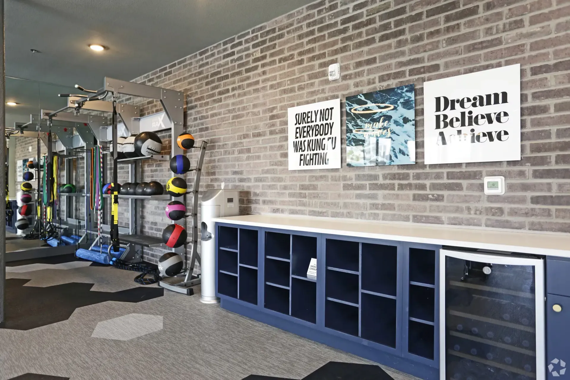 Fitness center with weight rack, medicine balls, and resistance bands against a brick wall.
