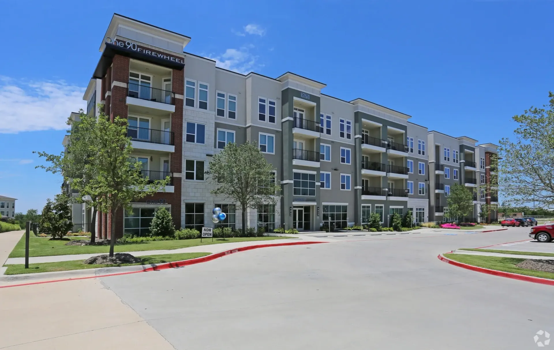 Exterior view of a modern apartment building with balconies and landscaped entry.