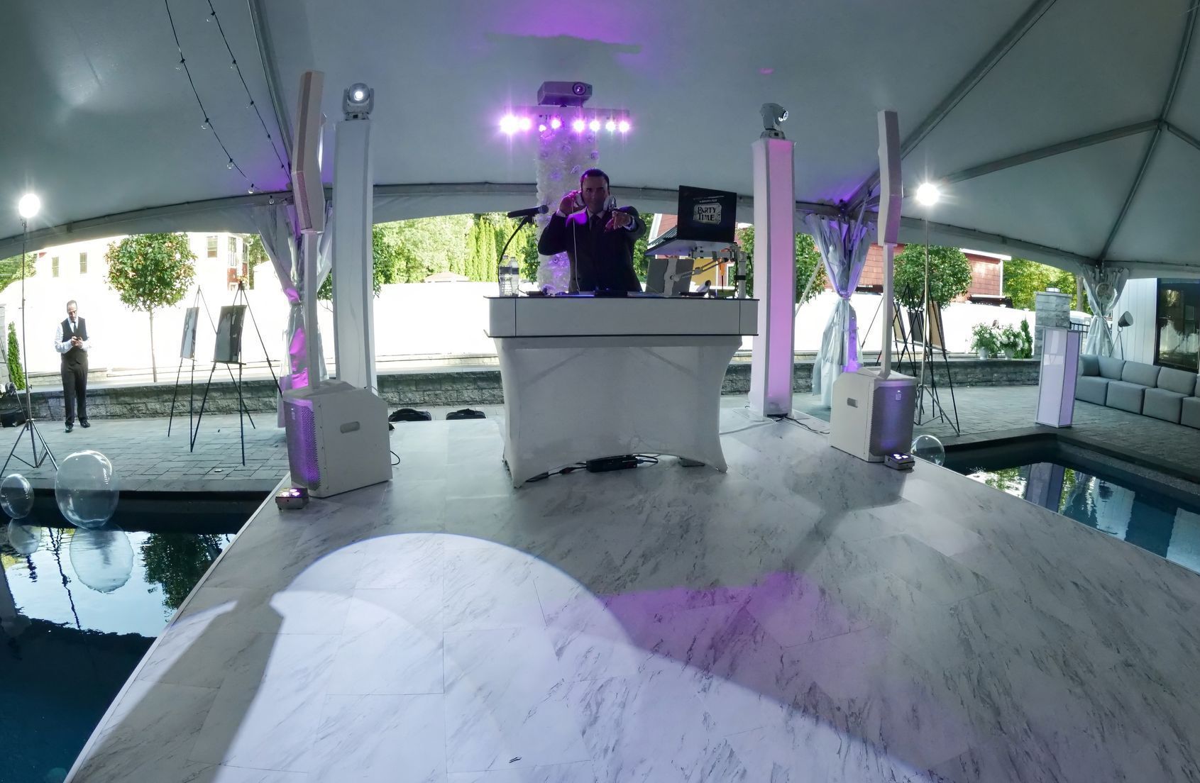 A dj is playing music in a tent next to a pool.