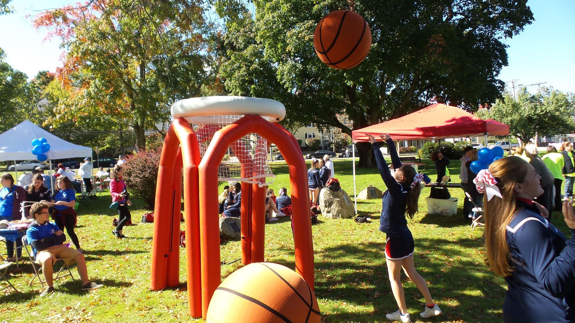 A group of people are playing Party Time Events Colossal Basketball in a park in Andover, MA