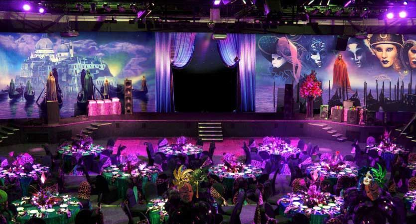 A large room filled with tables and chairs and purple lights.