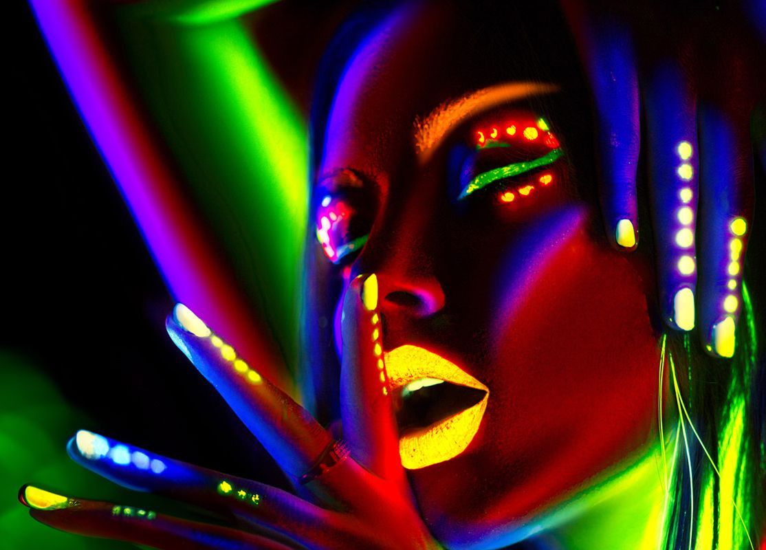 A woman with glow in the dark makeup on her face and nails.