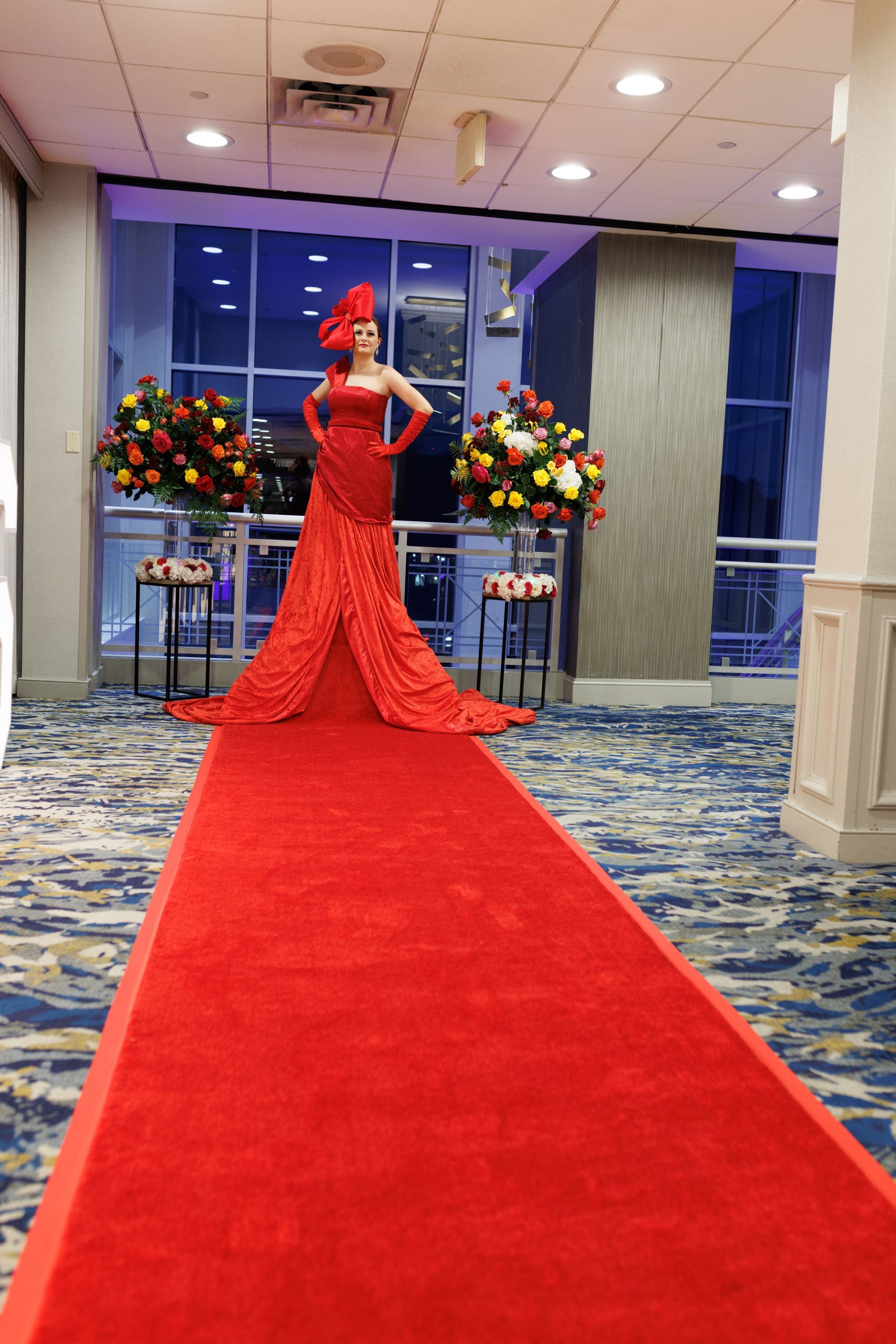 A woman in a red dress is walking down a red carpet.