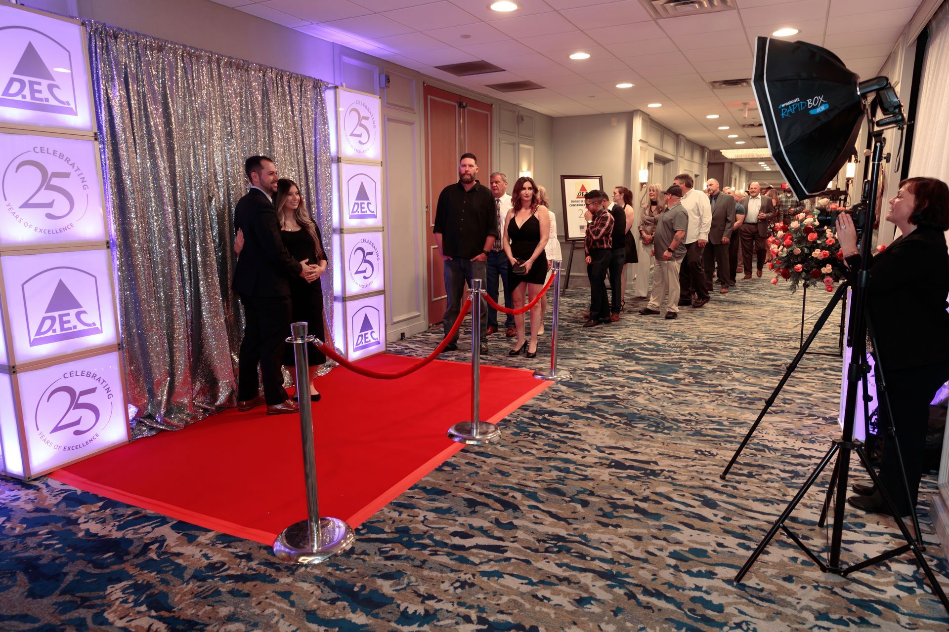 A woman is taking a picture of a group of people standing on a red carpet.