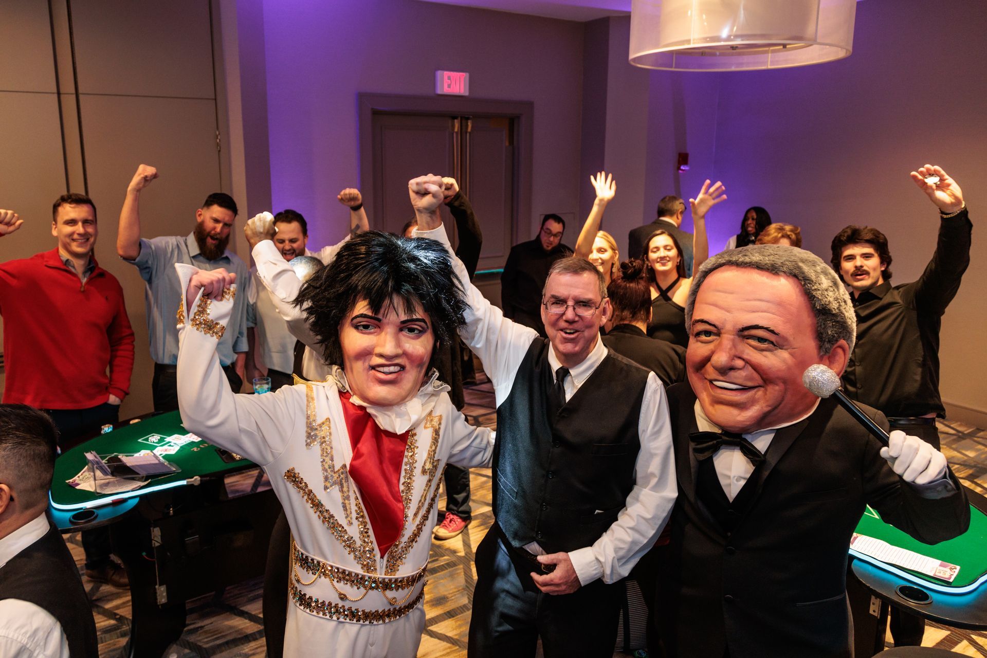 A group of people are standing in a room with elvis presley and frank sinatra masks.