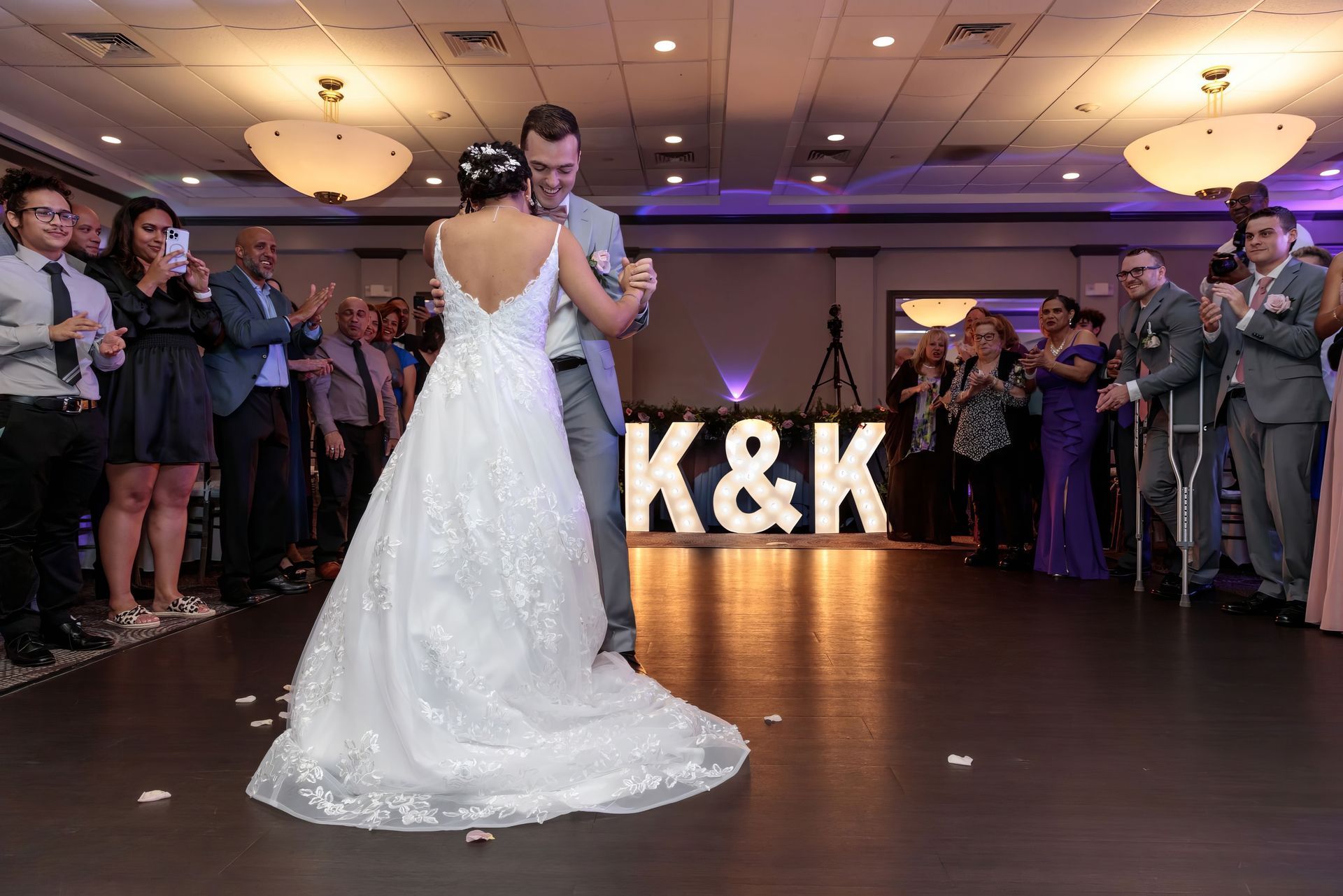 A bride and groom are dancing in front of a sign that says k & k.
