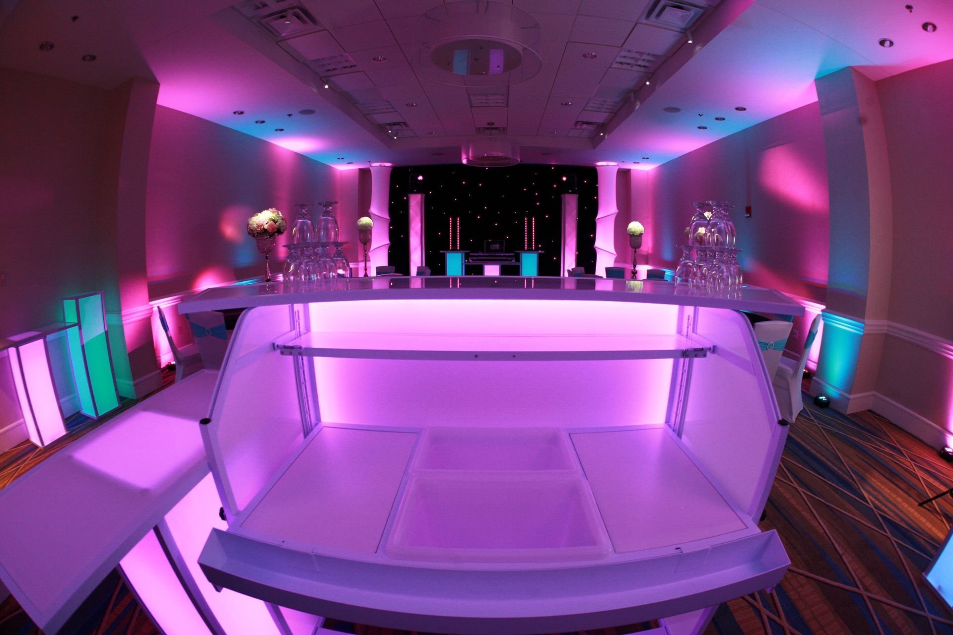 A large room with purple lights and a bar in the middle